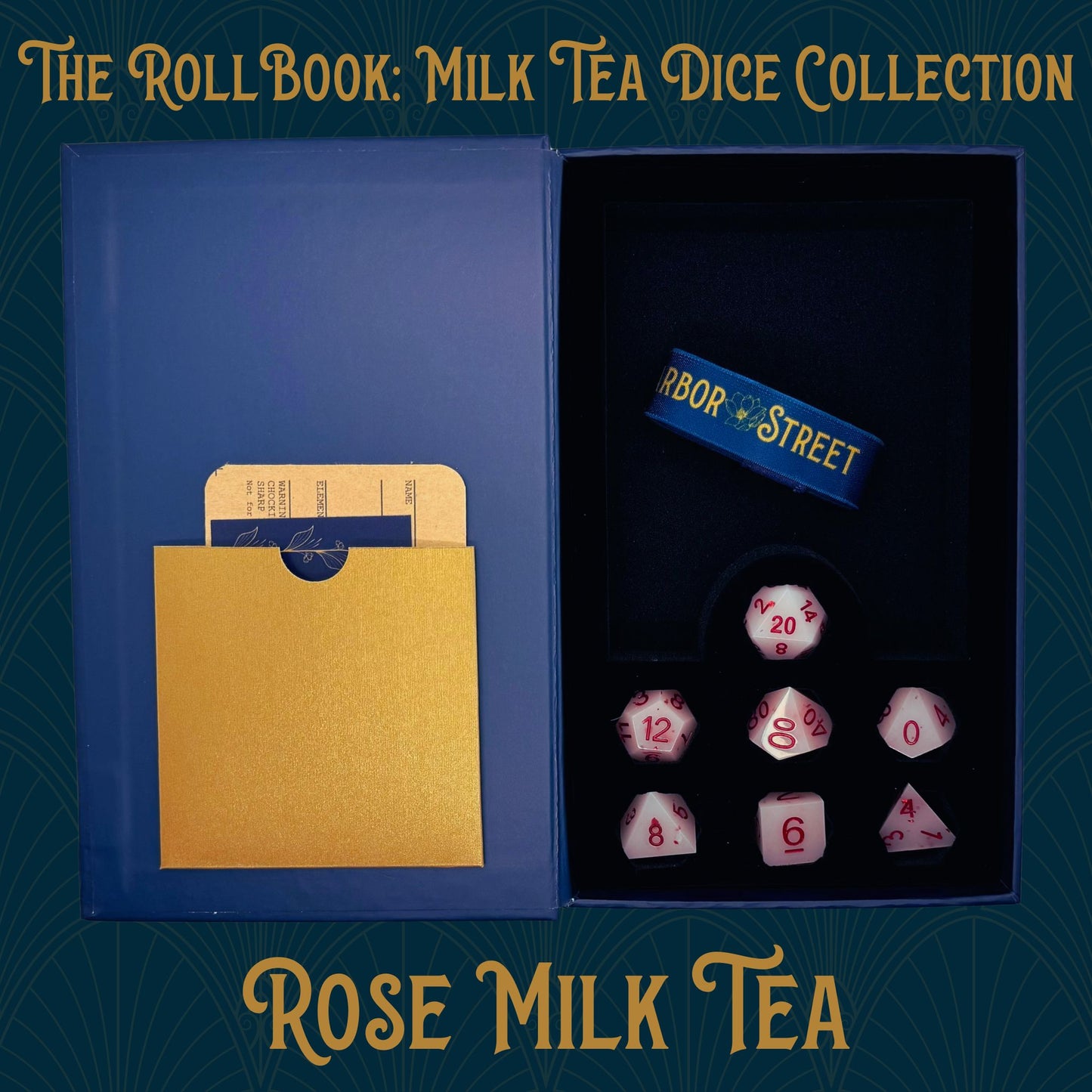 Blue book box with Rose Milk Tea themed seven polyhedral dice collection. Blue elastic band with the Harbor Street logo. Gold paper pocket